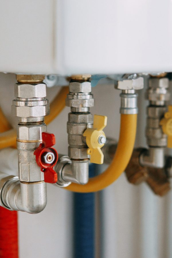 Close-up view of water heater pipes and valves in a utility room, featuring colorful connectors and tubes. Essential components for heating system maintenance and operation. Gas boiler taps. Close-up view of water heater pipes and valves in a utility room, featuring colorful connectors and tubes. Essential components for heating system maintenance and operation. Gas boiler taps.