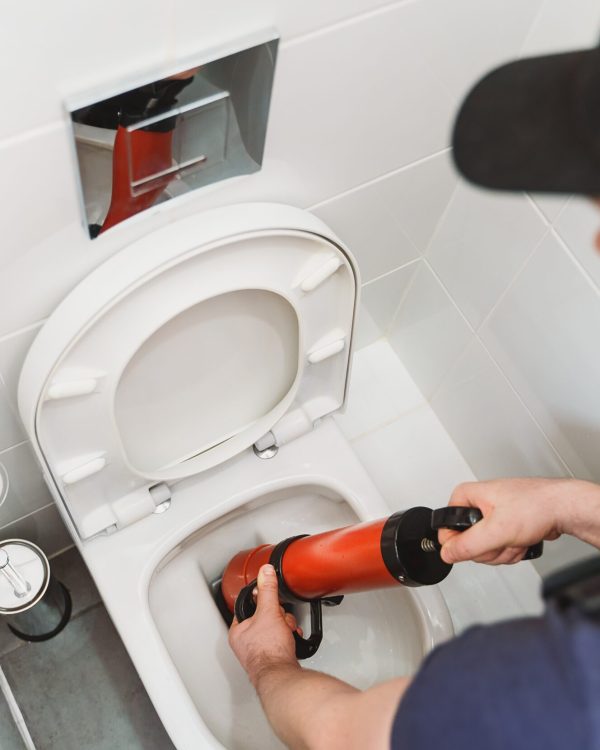 Plumber unclogging toilet with professional force pump cleaner. Plumber unclogging toilet with professional force pump cleaner.