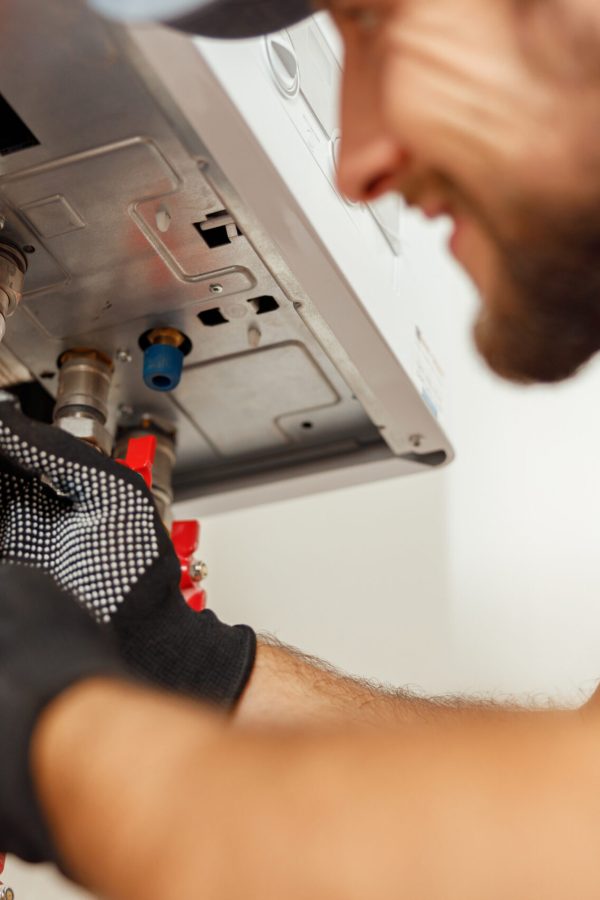 Closeup of plumber using screwdriver while installing new steel hot water central heating system in apartment Closeup of plumber using screwdriver while installing new steel hot water central heating system in apartment. Manual work, maintenance, repair service concept